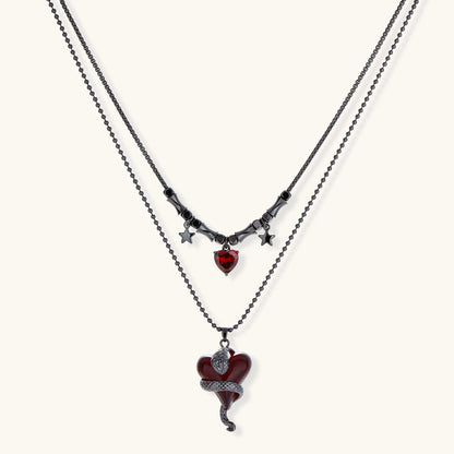 Dark layered necklace set with black chains and red heart pendants, featuring gothic snake design on white background